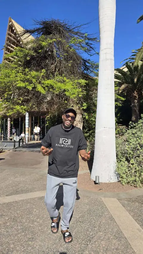 Oluseyi outdoors under the palms, relaxed and mid-laugh