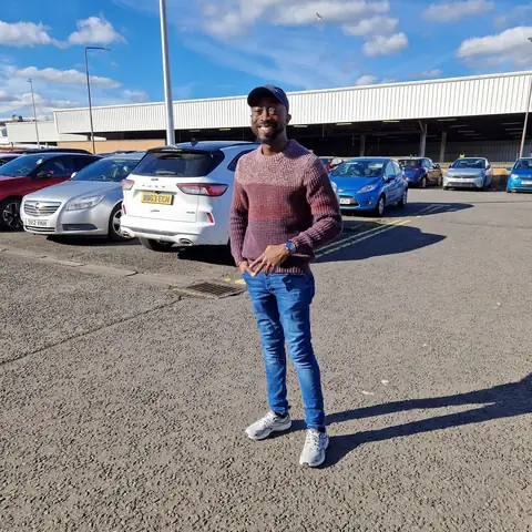 Oluseyi in a maroon jumper, hands in pockets