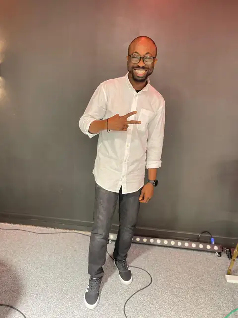 Oluseyi in a white shirt, pointing to camera