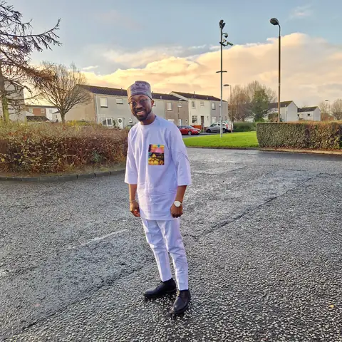 Oluseyi in white agbada and fila at dusk